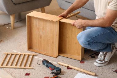 Evdeki çekmecede ahşap masa montajı yapan genç adam.