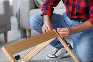 Genç adam evdeki masayı topluyor, yakın plan.