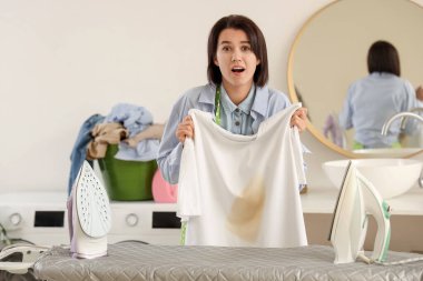 Evde çamaşır ütülerken endişeli bir ev hanımı.