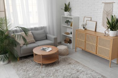 Oturma odasının iç tarafındaki pencere kenarındaki masa, kanepe ve bitkiler.