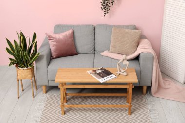 Oturma odasının iç tarafındaki pembe duvarın yanındaki masa ve kanepe.