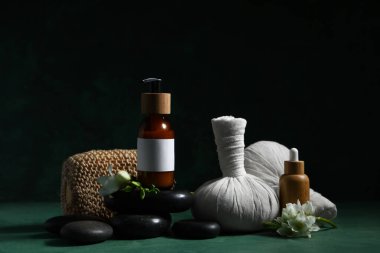 Kozmetik ürünleri şişeleri, spa aksesuarları ve koyu renk arka planda çiçekler içeren kompozisyon