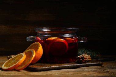 Ahşap arka planda elma ve portakallı sıcak sıcak sıcak şarap demliği.