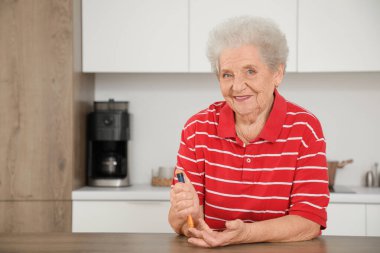 Diyabetik kıdemli kadın mutfaktaki masada tükenmez kalem kullanıyor.