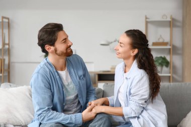 Evdeki kanepede el ele tutuşan evli çift.