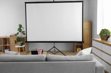 Gri kanepesi, patlamış mısırı ve kahve masasında modern projektörü olan şık bir oturma odası.