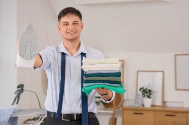 Evde demir ve giysi yığınıyla yakışıklı, genç ve mutlu bir iş adamı.