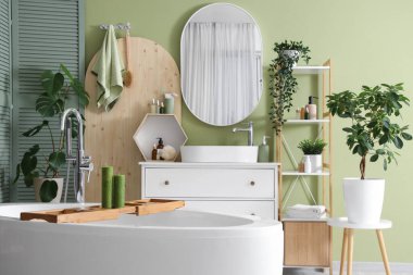 Banyonun içinde küvet, lavabo ve yeşil bitkiler var.