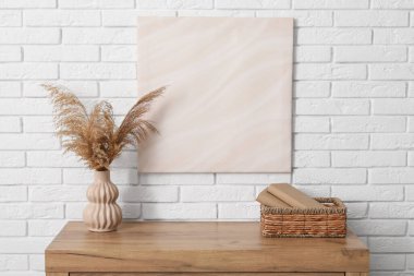 Çimenli çekmeceler, sepetli kitaplar ve odadaki beyaz tuğlalı duvarda resim. Yakın çekim.