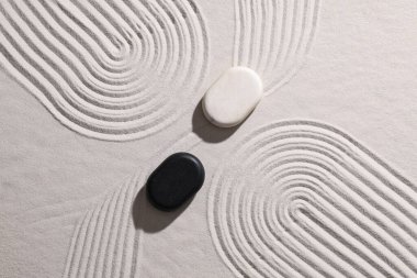 Üzerinde çizgiler olan beyaz kumlar üzerinde taşlar. Yin Yang konsepti