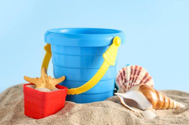 Plaj oyuncakları ve açık mavi arka planda kum