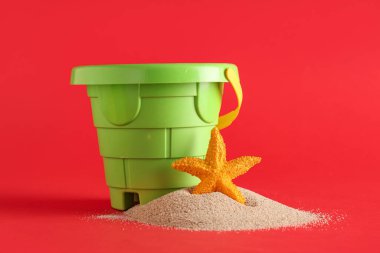 Kırmızı arka planda plastik kova ve kum