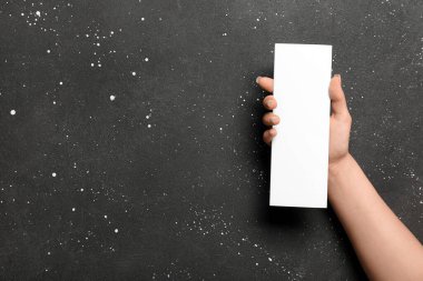 Siyah arka planda boş broşürlü bir kadın.