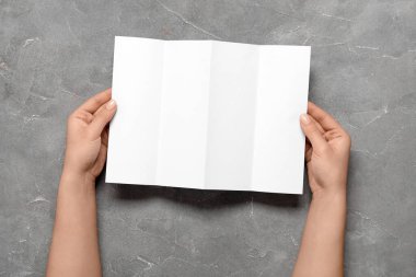 Gri arka planda boş broşürlü kadın elleri