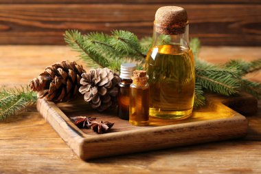 Ahşap zemin üzerinde kozalaklı koni yağı şişeleri olan tahta.