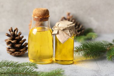 Arkaplanda kozalaklı koni yağı olan şişeler.