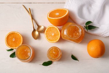 Beyaz ahşap arka planda lezzetli turuncu reçel kavanozları