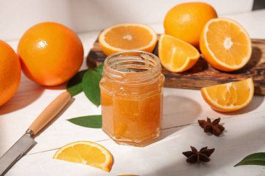 Beyaz ahşap arka planda lezzetli turuncu reçel kavanozu