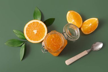 Yeşil arka planda bir kavanoz lezzetli portakal reçeli