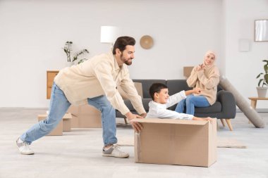 Happy Muslim family having fun in room on moving day clipart