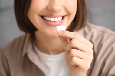 Evde diş eti çiğneyen genç bir kadın, yakın plan.