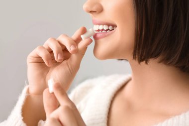 Genç bir kadın arka planda diş eti yiyor.