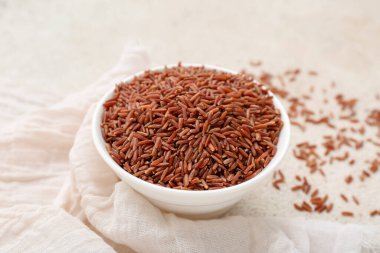 Açık arkaplanda çiğ kahverengi pirinç ile kase