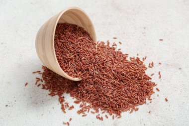 Açık arkaplanda çiğ kahverengi pirinç ile ters çevrilmiş kase