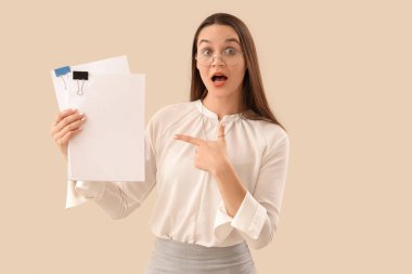 Şok olmuş sekreter bej arka plandaki boş kağıtlara işaret ediyor.