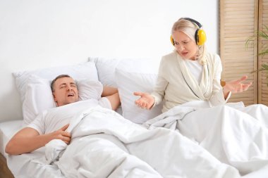 Kocasının yatak odasında horlaması yüzünden işitme koruyucuları olan olgun bir kadın uyuyamaz.