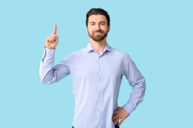 Genç adam mavi arka planı işaret ediyor.