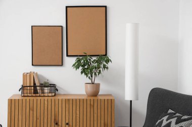 Oturma odasının içinde lamba, çekmece ve boş çerçeveler var.