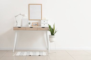 Masa lambası, takvimi ve beyaz duvarın yanında mumları olan modern masa.