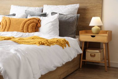 Yatak odasının içinde rahat yatak ve lamba komodinin üzerinde.