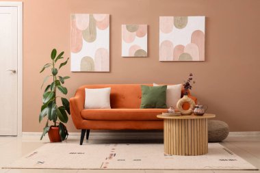 Kanepesi, masası ve tabloları olan şık bir oturma odası.