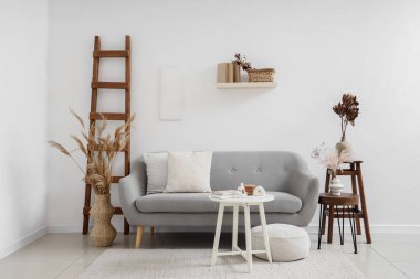 Şık oturma odasının içinde kanepe, masa ve kurumuş çiçekler var.