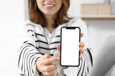 Evde boş cep telefonu kullanan genç bir kadın, yakın plan.