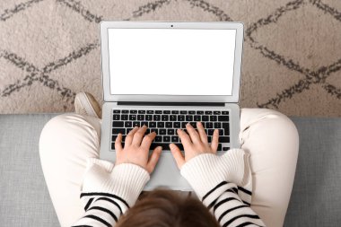 Evde boş dizüstü bilgisayar kullanan genç bir kadın.