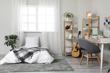 Yatak, işyeri ve raf üniteleri olan bir gencin odasının içinde.