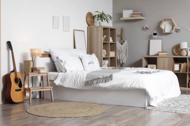 Yatağı, gitarı ve kitaplığı olan hafif gencin odasının içinde.