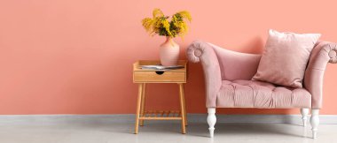 Masasında mimoza çiçekleri olan vazo ve mercan duvarının yanındaki kanepe. Tasarım için pankart