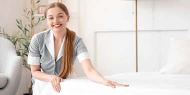 Otel odasında yatak yapma genç Oda hizmetçisi