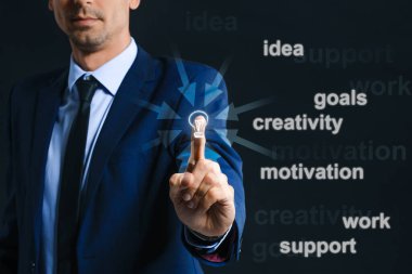 Genç iş adamı karanlık arka planda farklı sözcüklerle sanal ekran kullanıyor. Hedef kavramı