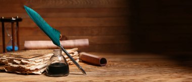 Eski kitap, tükenmez kalem, mürekkep hokkası ve tahta zemin üzerinde metin için boşluk olan parşömenler