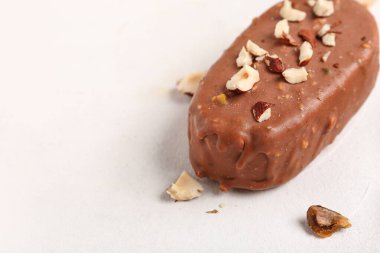 Lezzetli çikolata kaplı dondurma, beyaz masada ezilmiş fındıklar, yakın plan.