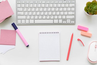 Beyaz arkaplanda yapışkan notlar, klavye ve defter içeren kompozisyon