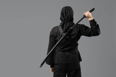 Gri arka planda kılıcı olan erkek ninja.