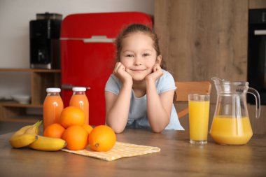 Mutfakta bir bardak meyve suyu olan küçük bir kız.