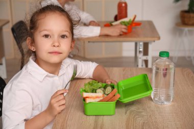 Küçük kız öğle yemeğini sınıfta yiyor.