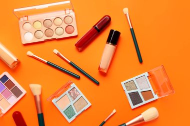 Güzel göz falı paletleri ve turuncu arka planda farklı dekoratif kozmetikler.